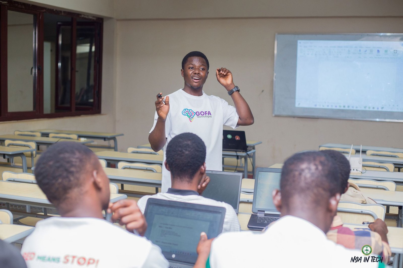 A facilitator demonstrating Microsoft Word to learners using laptops.
