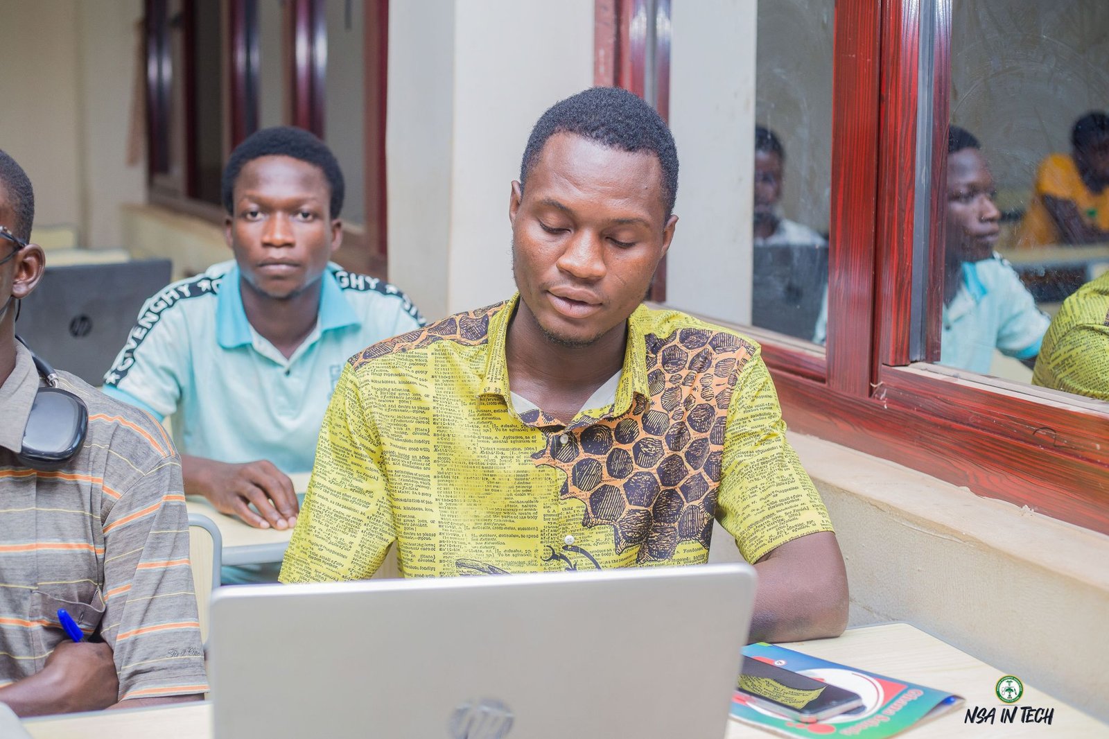 A participant working at a laptop with other learners nearby.